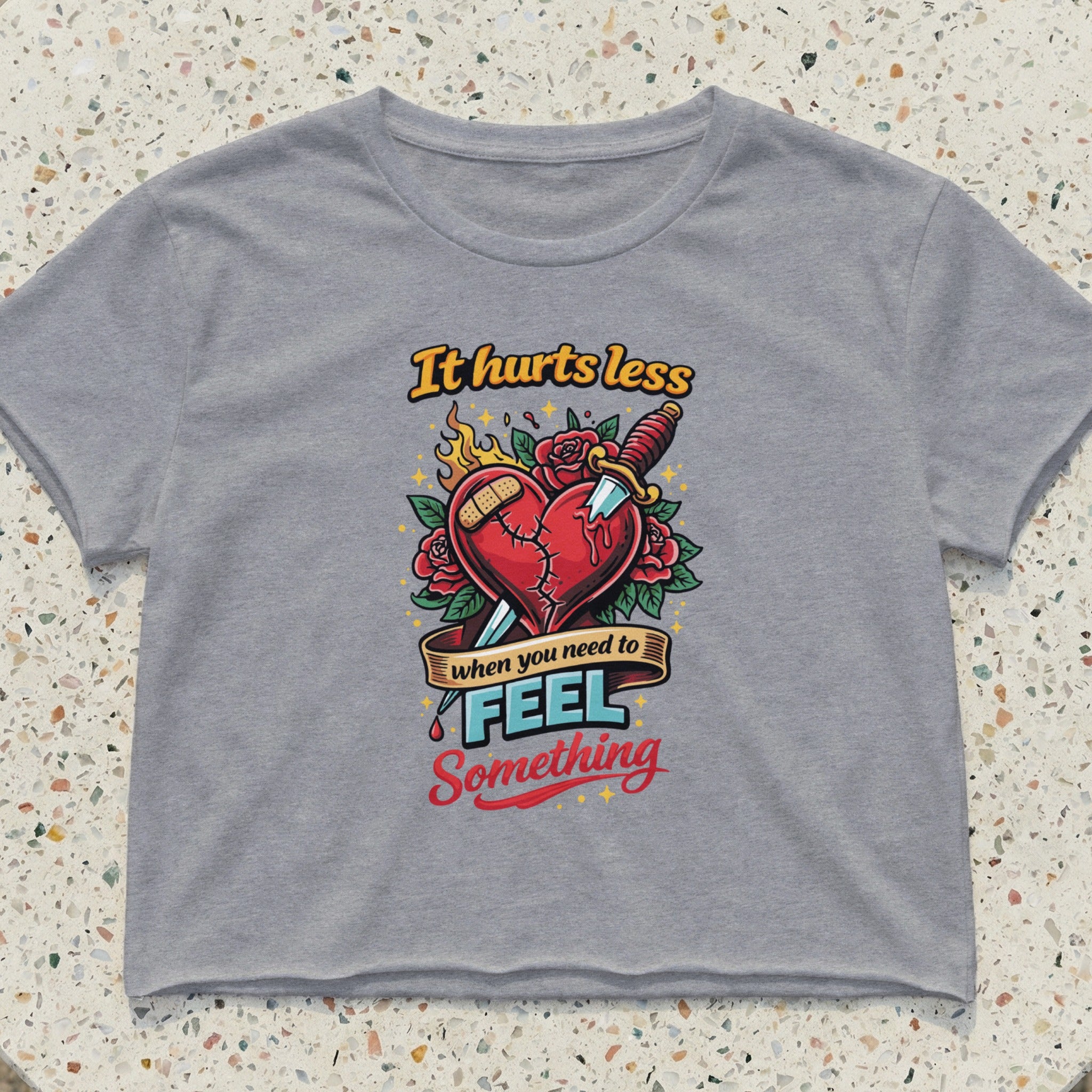 Gray cropped t-shirt with "It hurts less when you need to feel something" text and heart design.