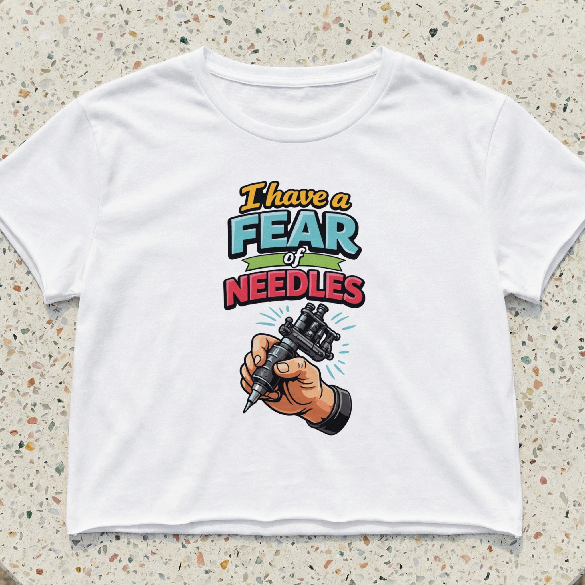 White crop top with "I have a fear of NEEDLES" and a tattoo gun.