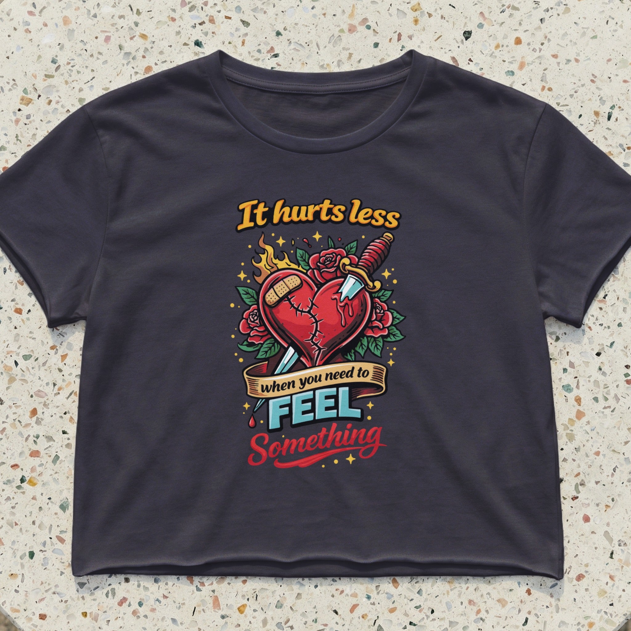 Dark gray crop top with "It hurts less when you need to feel something" graphic.