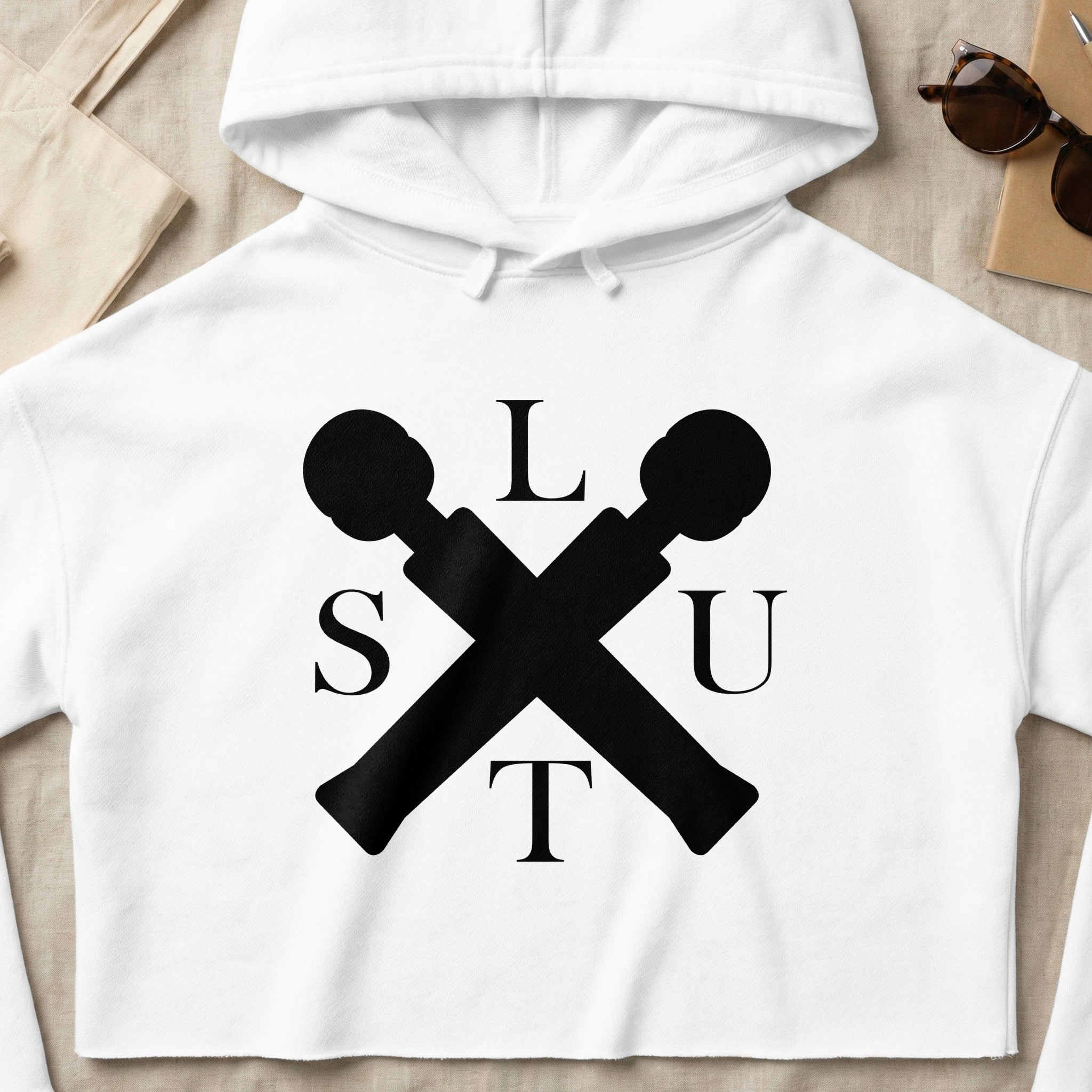 White cropped hoodie with black "SLUT" text and crossed microphones graphic.
