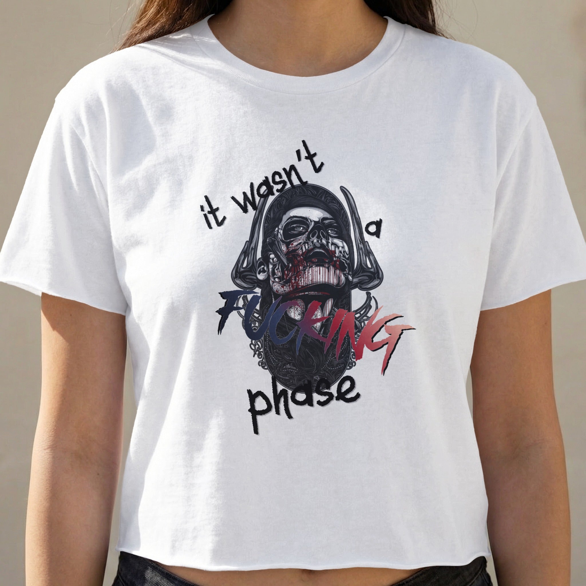 White crop top with skull graphic and "it wasn't a fucking phase" text.