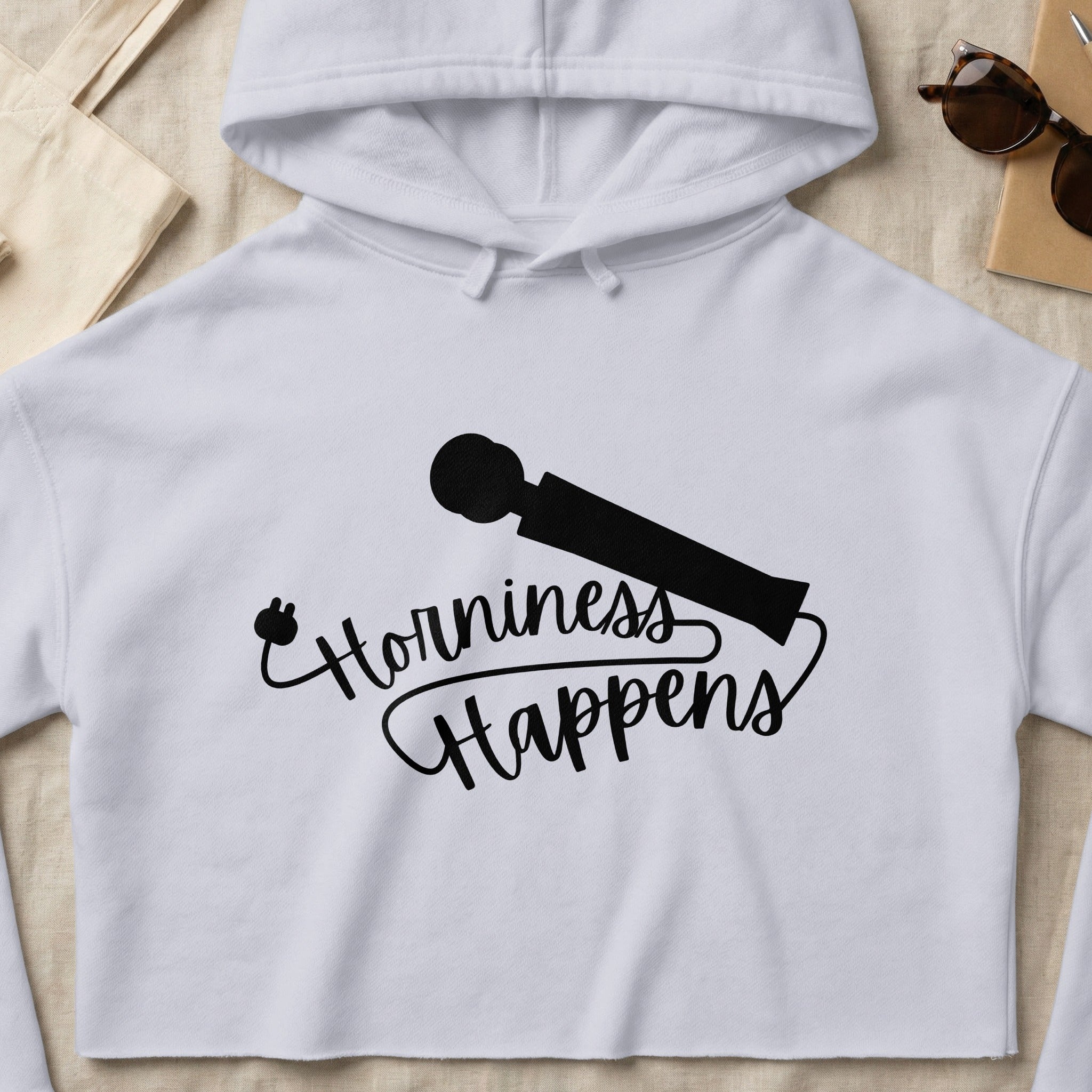 White cropped hoodie with "Horniness Happens" text and a silhouette of a personal massager.