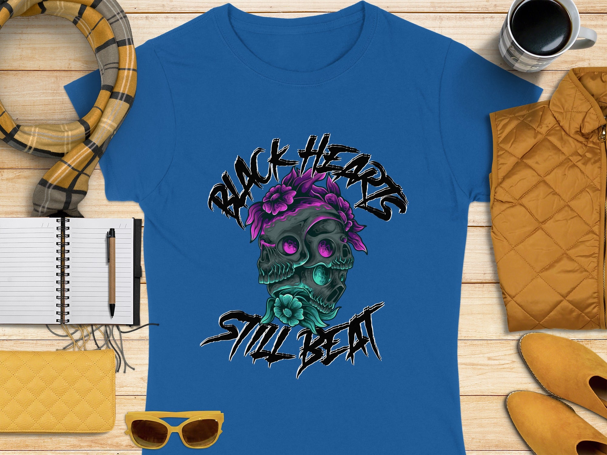 Blue t-shirt with "Black Hearts Still Beat" skull graphic, flowers, and autumn accessories.
