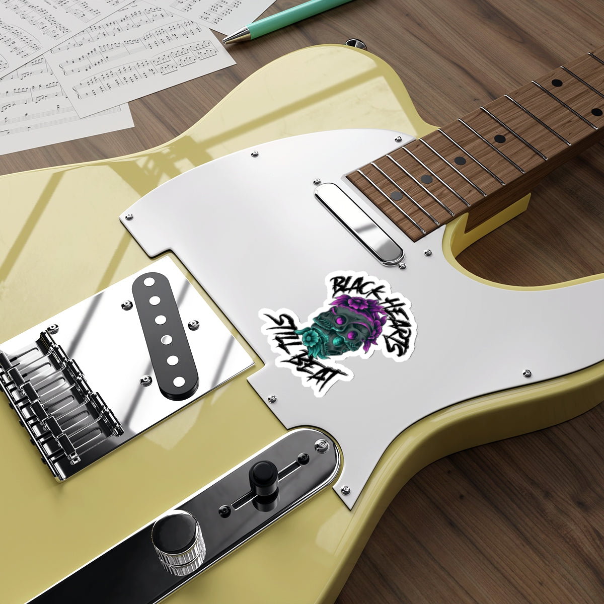 Skull sticker with "BLACK HEARTS STILL BEAT" text on a yellow electric guitar.