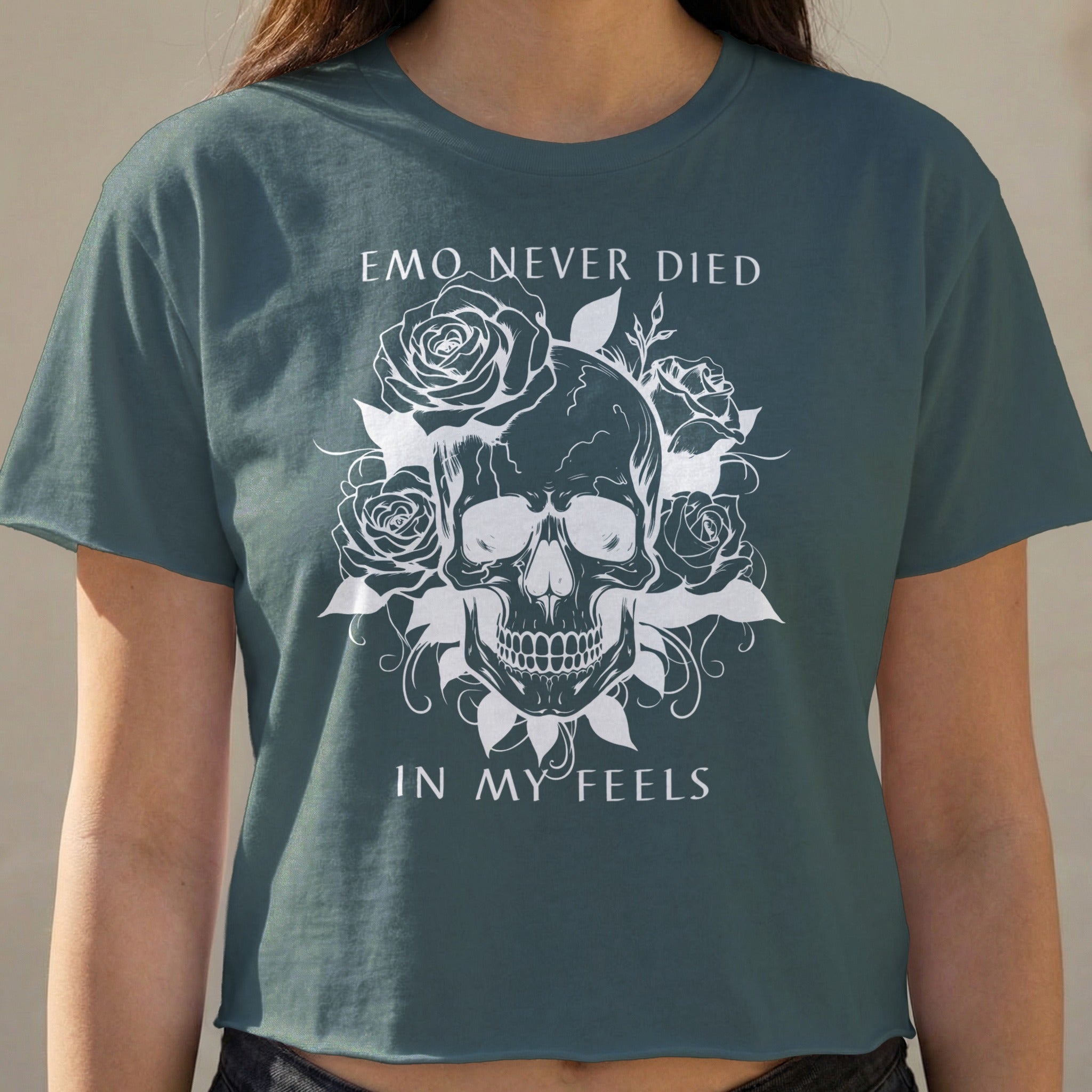 Dark teal cropped t-shirt with skull and roses graphic and text.