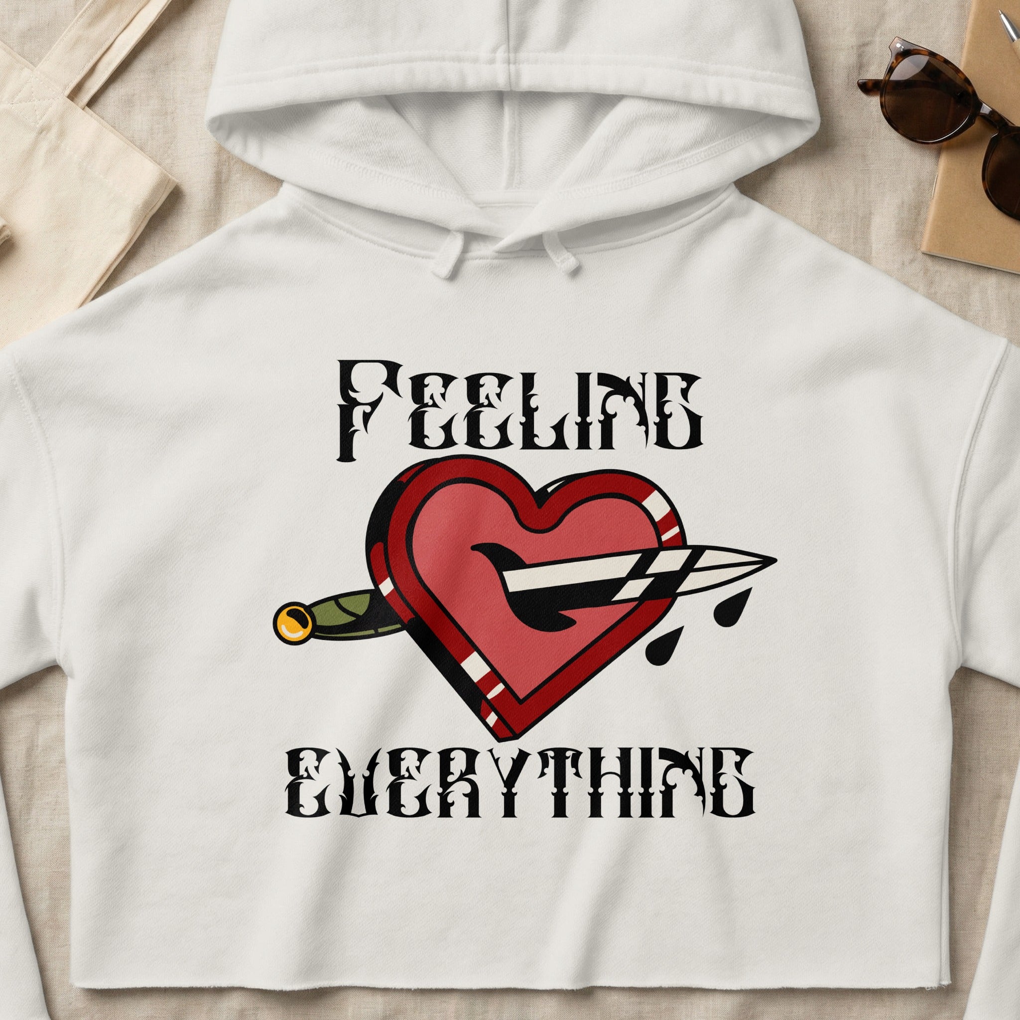 Cropped hoodie with red heart pierced by dagger, text "FEELING EVERYTHING".