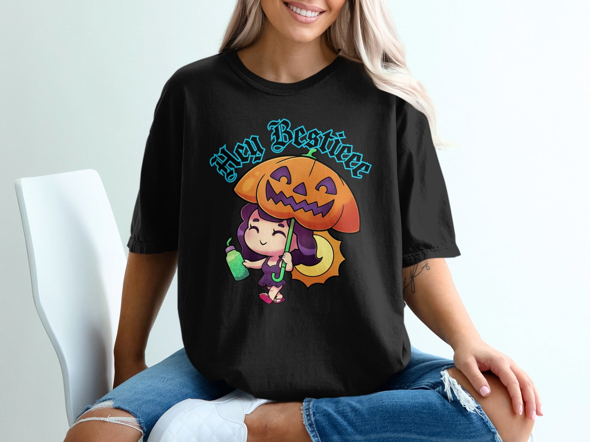 Black t-shirt with cartoon girl holding a drink under a pumpkin umbrella with text "Hey Bestieee".