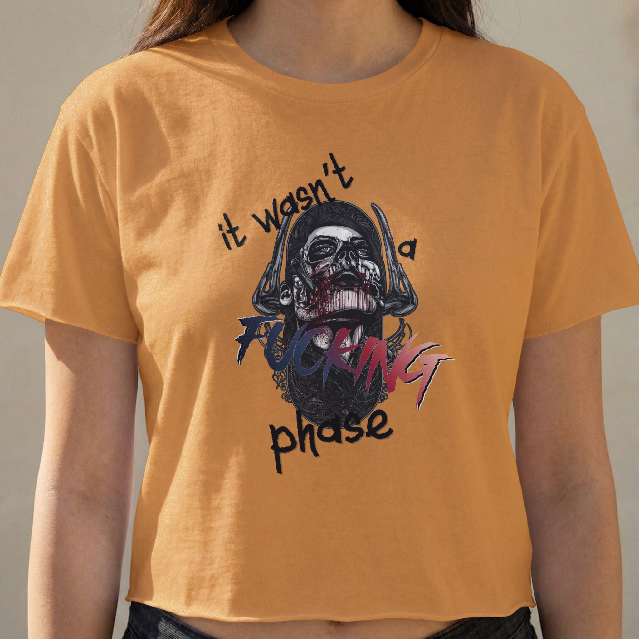 Orange crop top with graphic of skull and text "it wasn't a fucking phase".