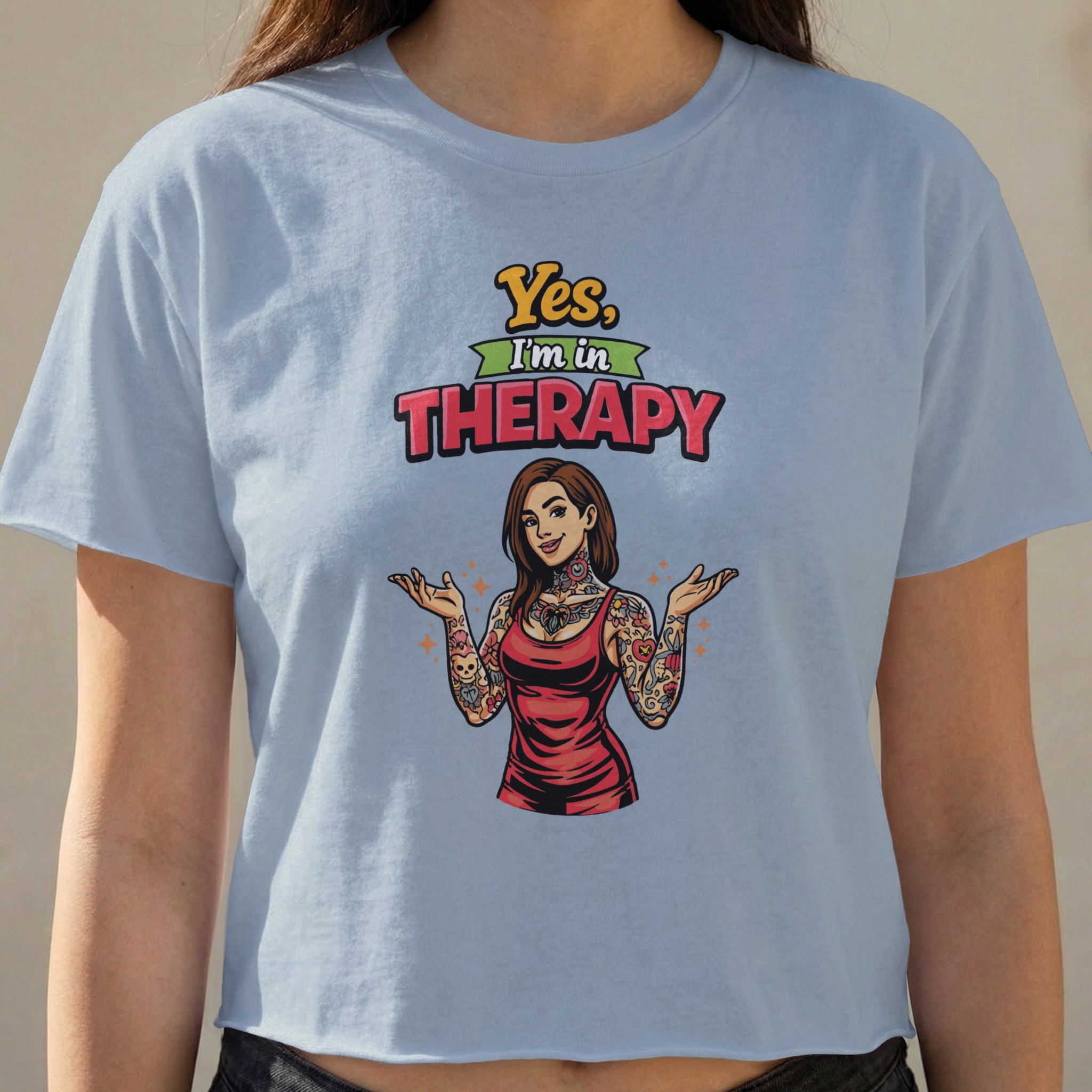 Woman wearing a crop top with "Yes, I'm in Therapy" text and tattooed graphic.
